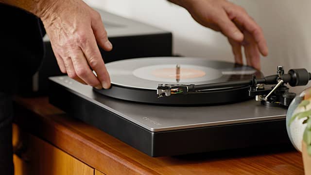 Hands placing a vinyl record on a turntable.