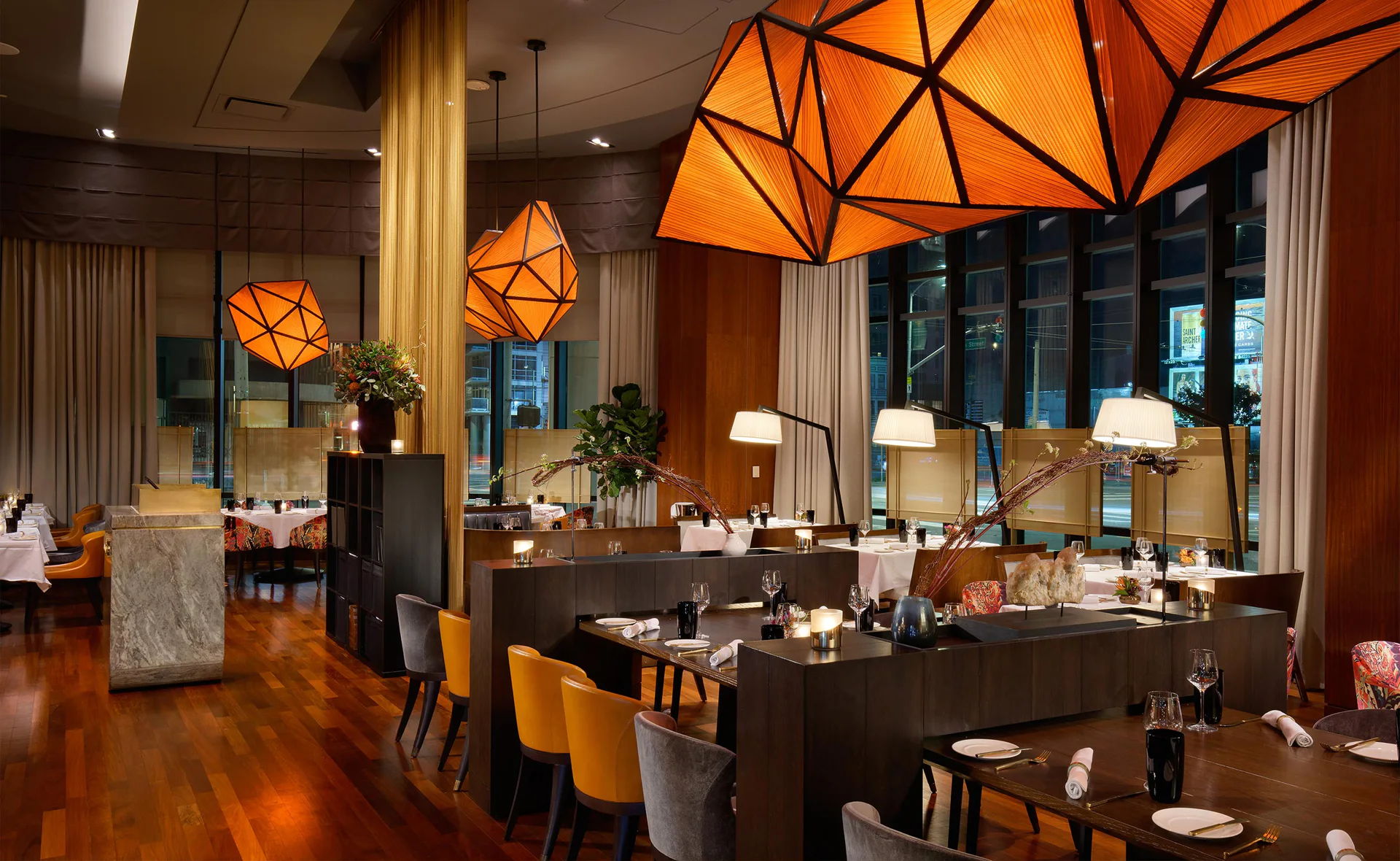 Interior of a modern restaurant with geometric lighting and wooden flooring.