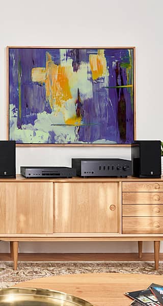 Modern living room with abstract art and audio equipment on a wooden cabinet.