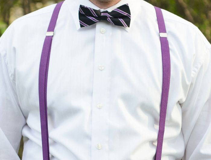 Man wearing dark purple skinny suspenders with a black and purple striped bow tie
