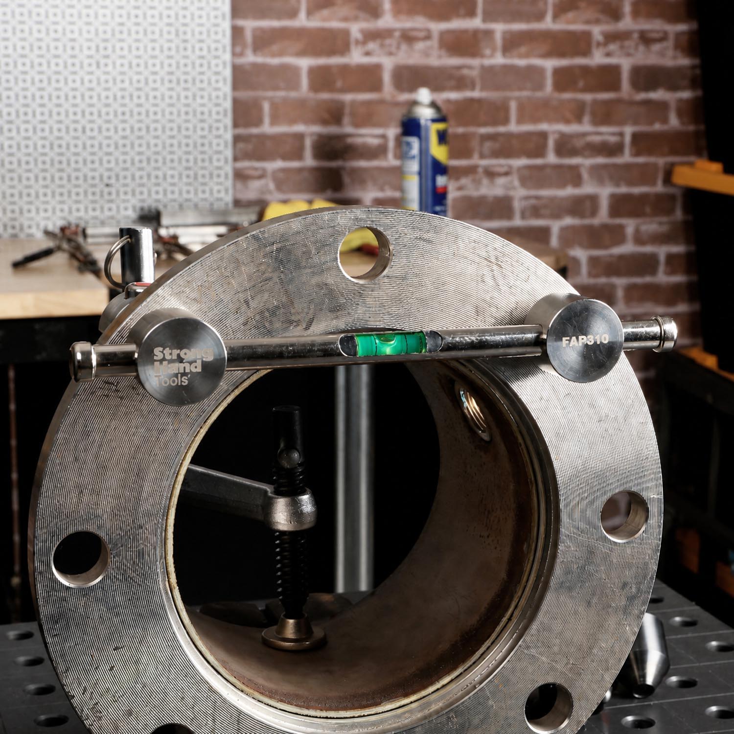 Metal flange with a level tool on a workbench.