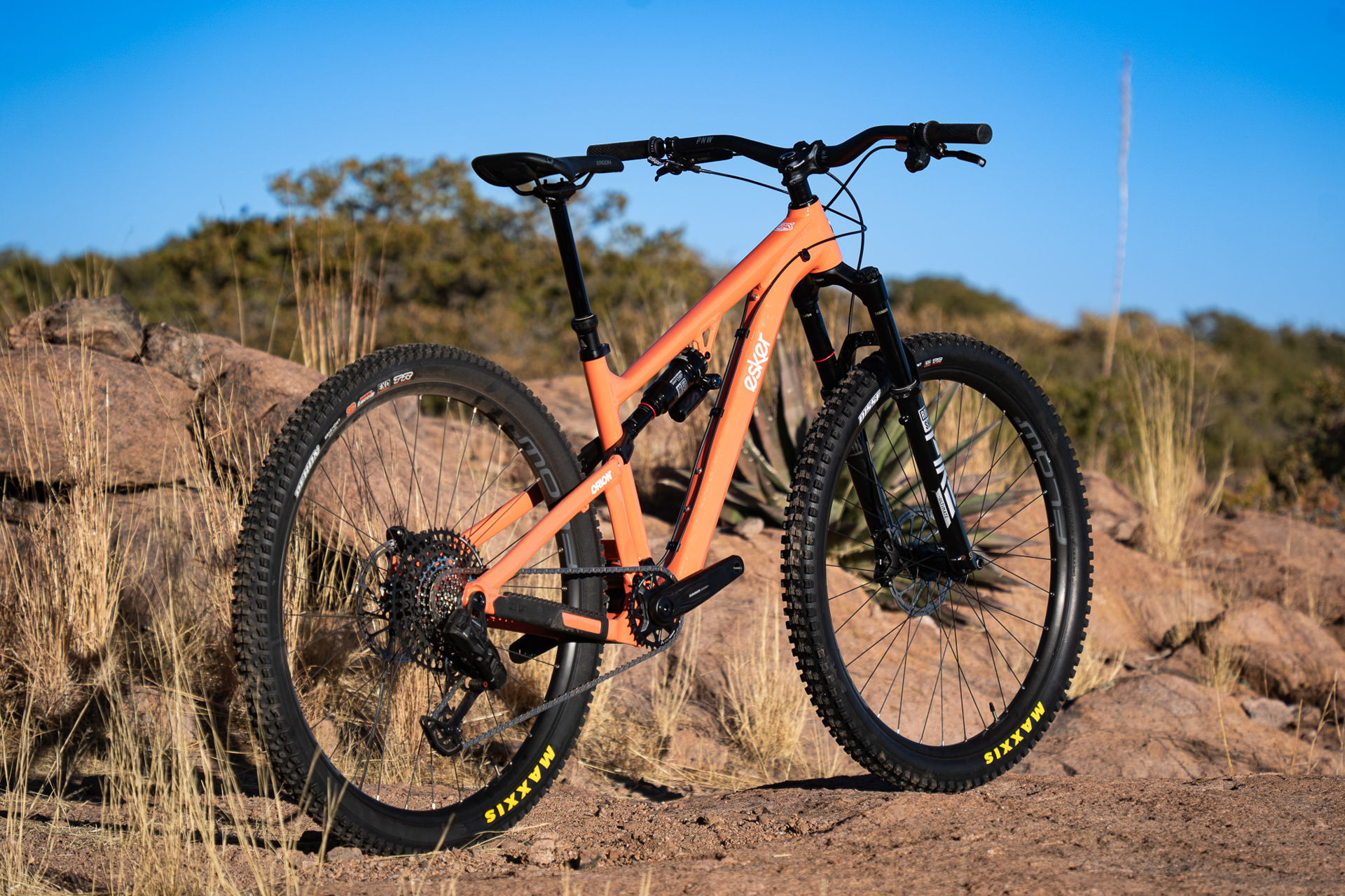 Orange Howdy mountain bike on rocky terrain under blue sky