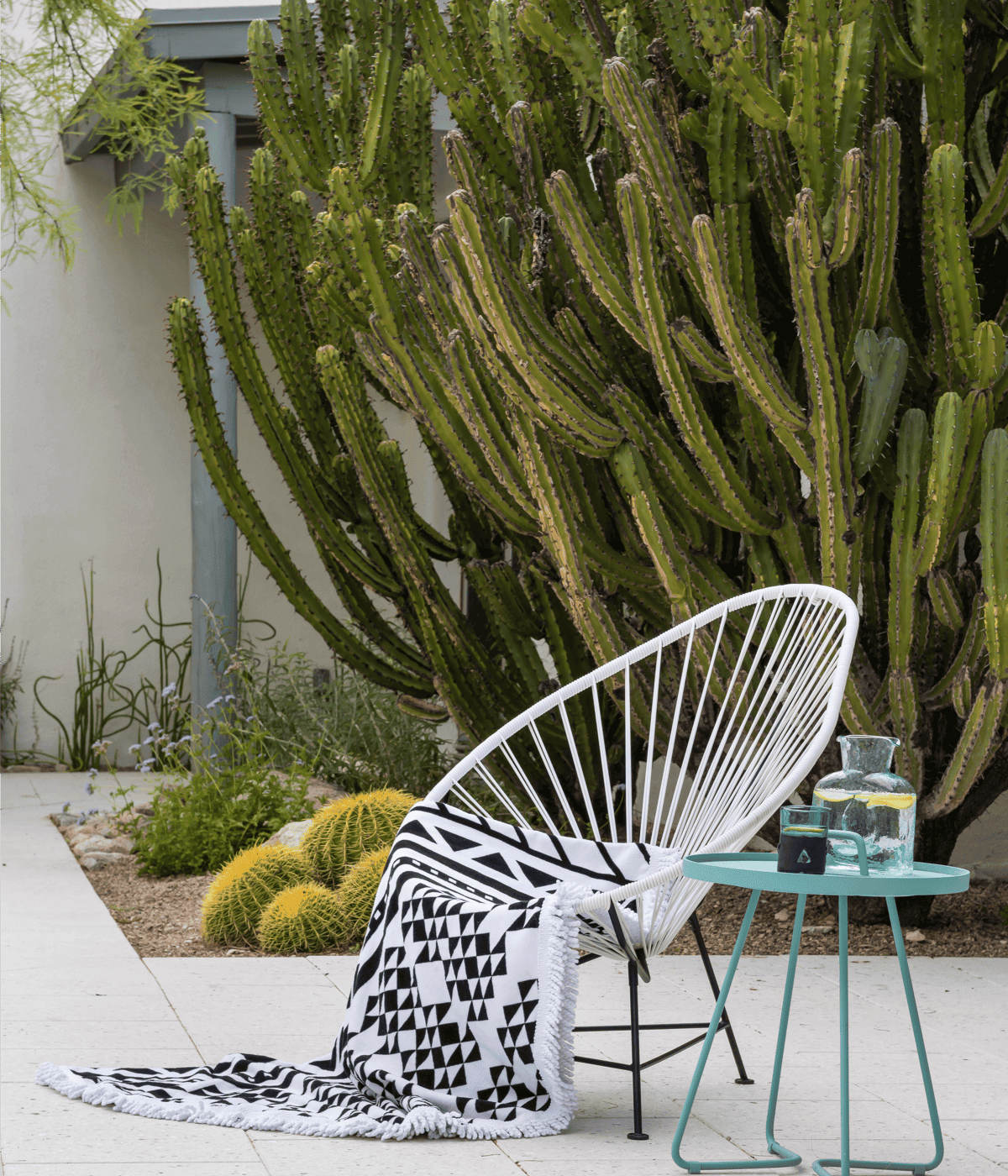 A striking modern woven chair with geometric outdoor blanket and torquoise side table.