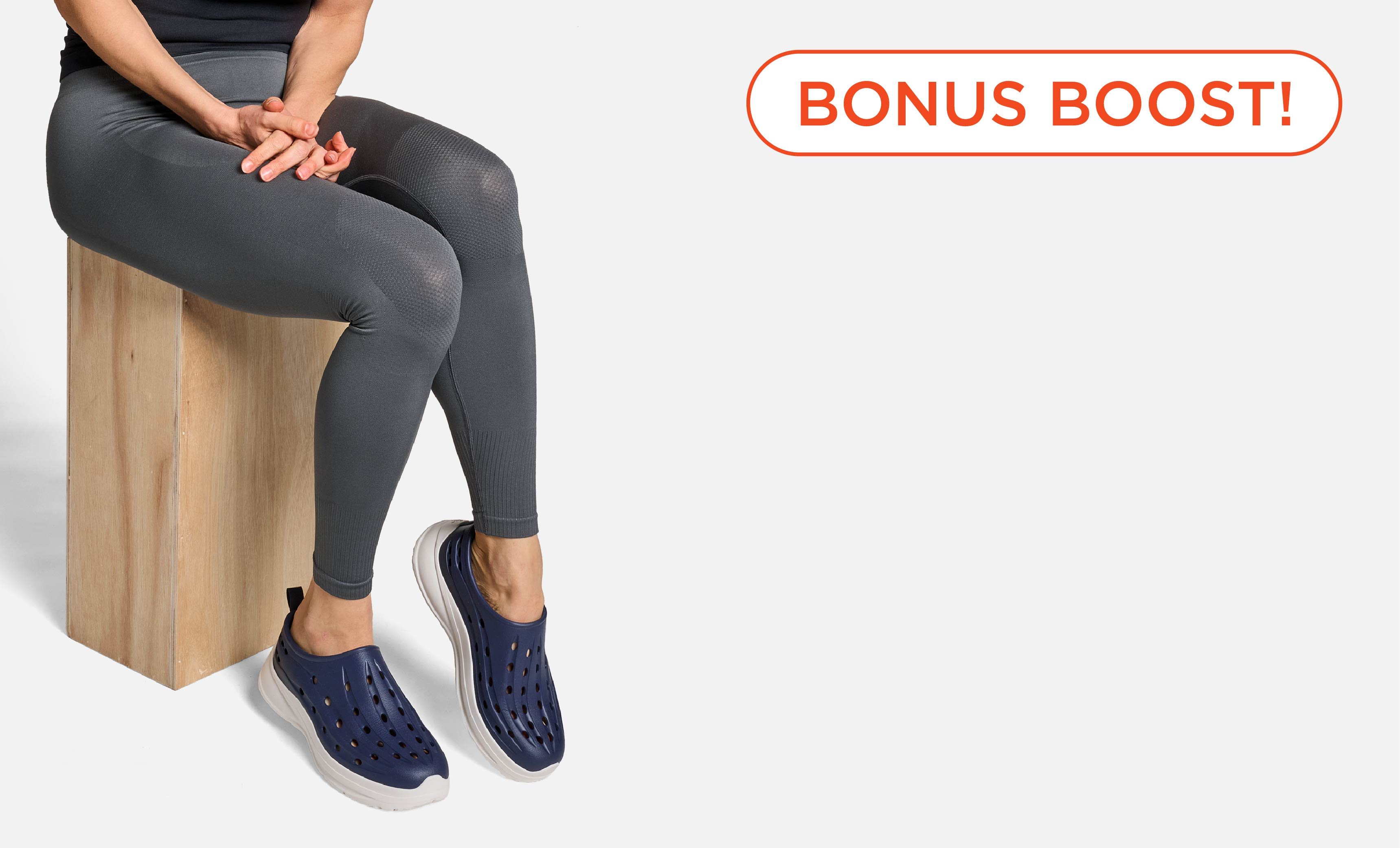 Person sitting on a block wearing gray leggings and navy shoes.