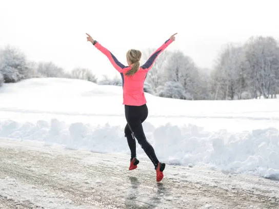 Woman running with arms in the air during winter