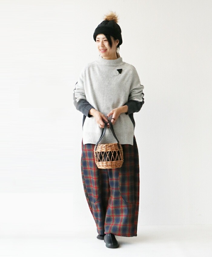 Woman in casual outfit holding a woven basket, standing against a white background.