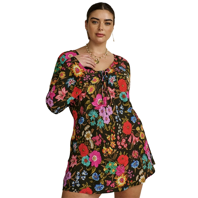 Model wearing a colorful floral dress with long sleeves and a tie detail.