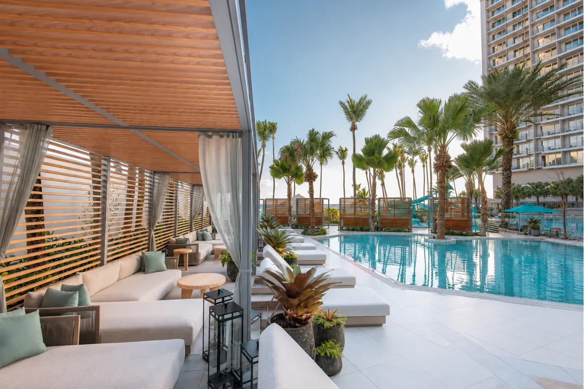 Rooftop Hotel pool cabana with Cabana, cushioned outdoor lounge seating overlooking a landscaped hotel pool deck