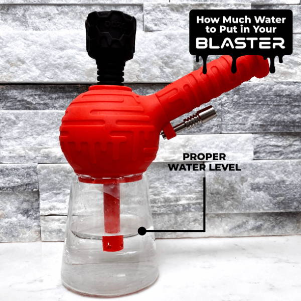 A red and black Ooze Blaster bong is shown filled with water. There is a white arrow that says FILL LINE pointing at the water level.