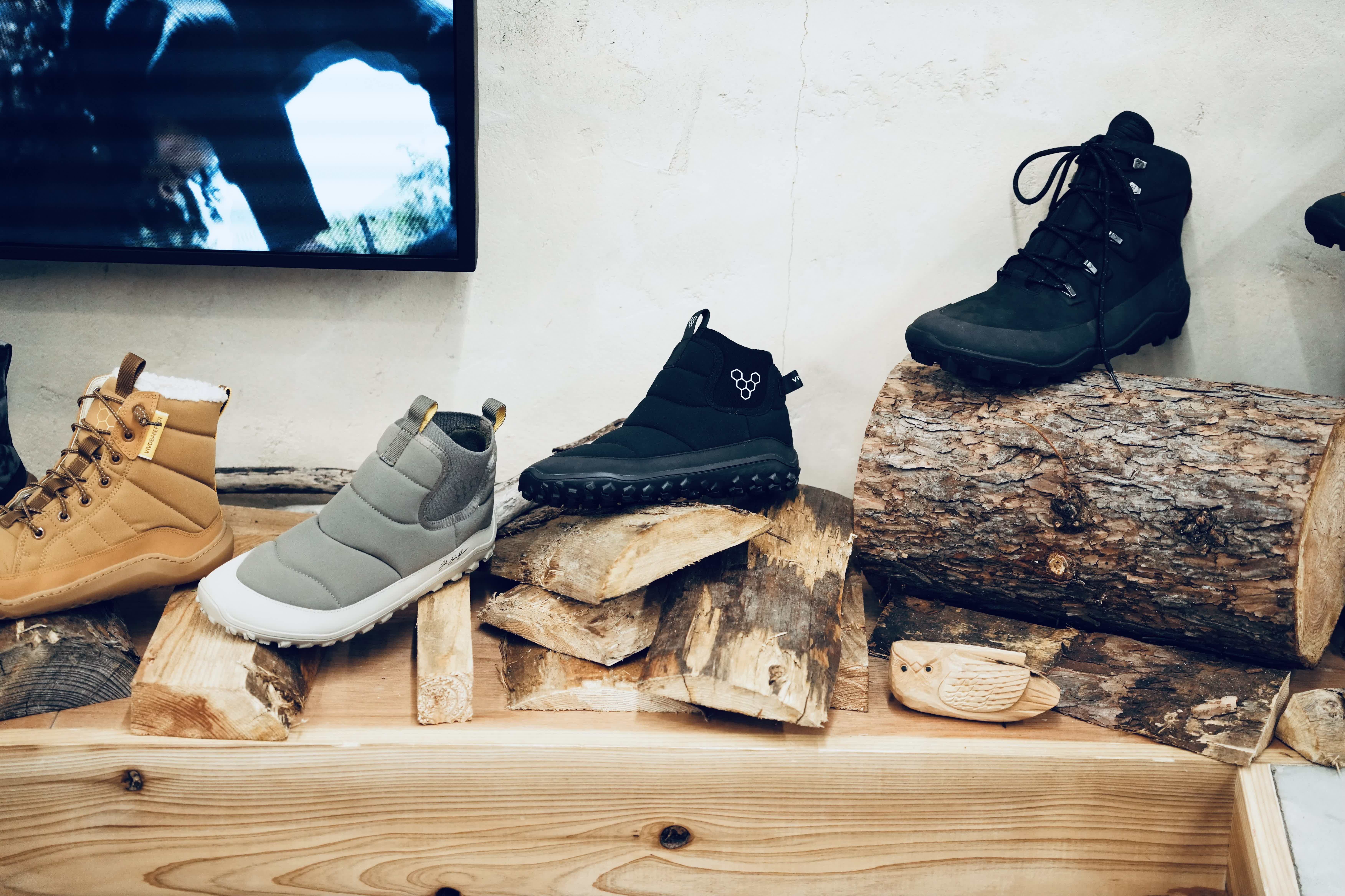 Three pairs of shoes displayed on wooden logs.