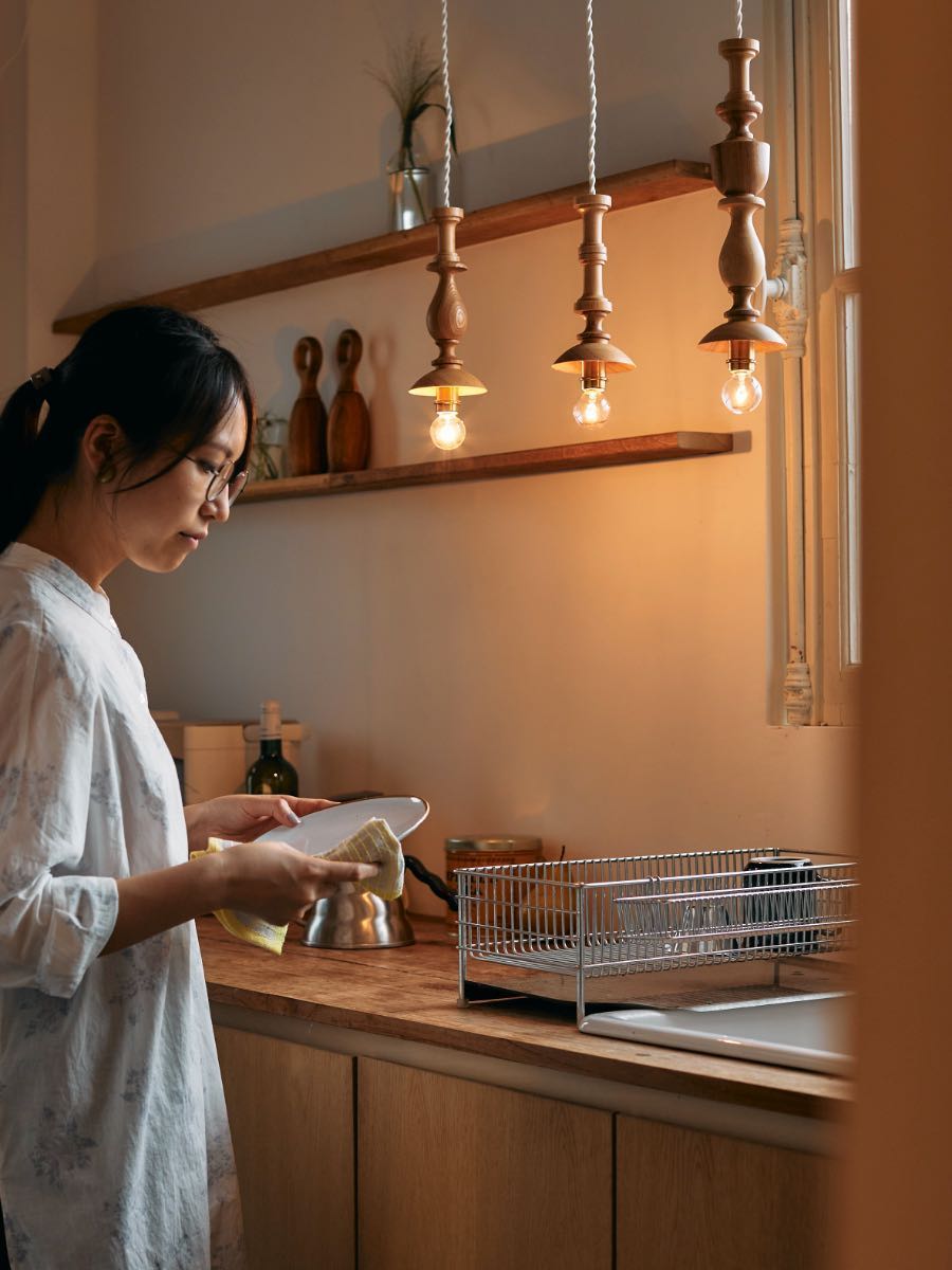Woman reading a book in a warmly lit kitchen.