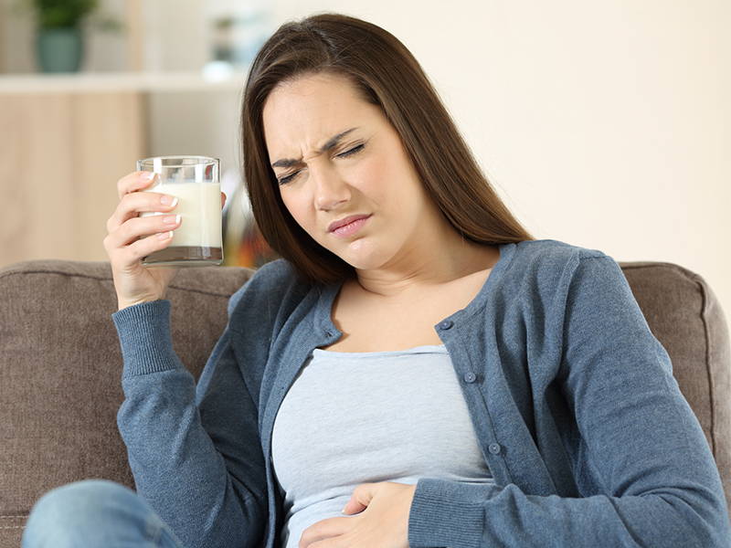 Een vrouw met een glas melk lijkt last te hebben van haar darmen