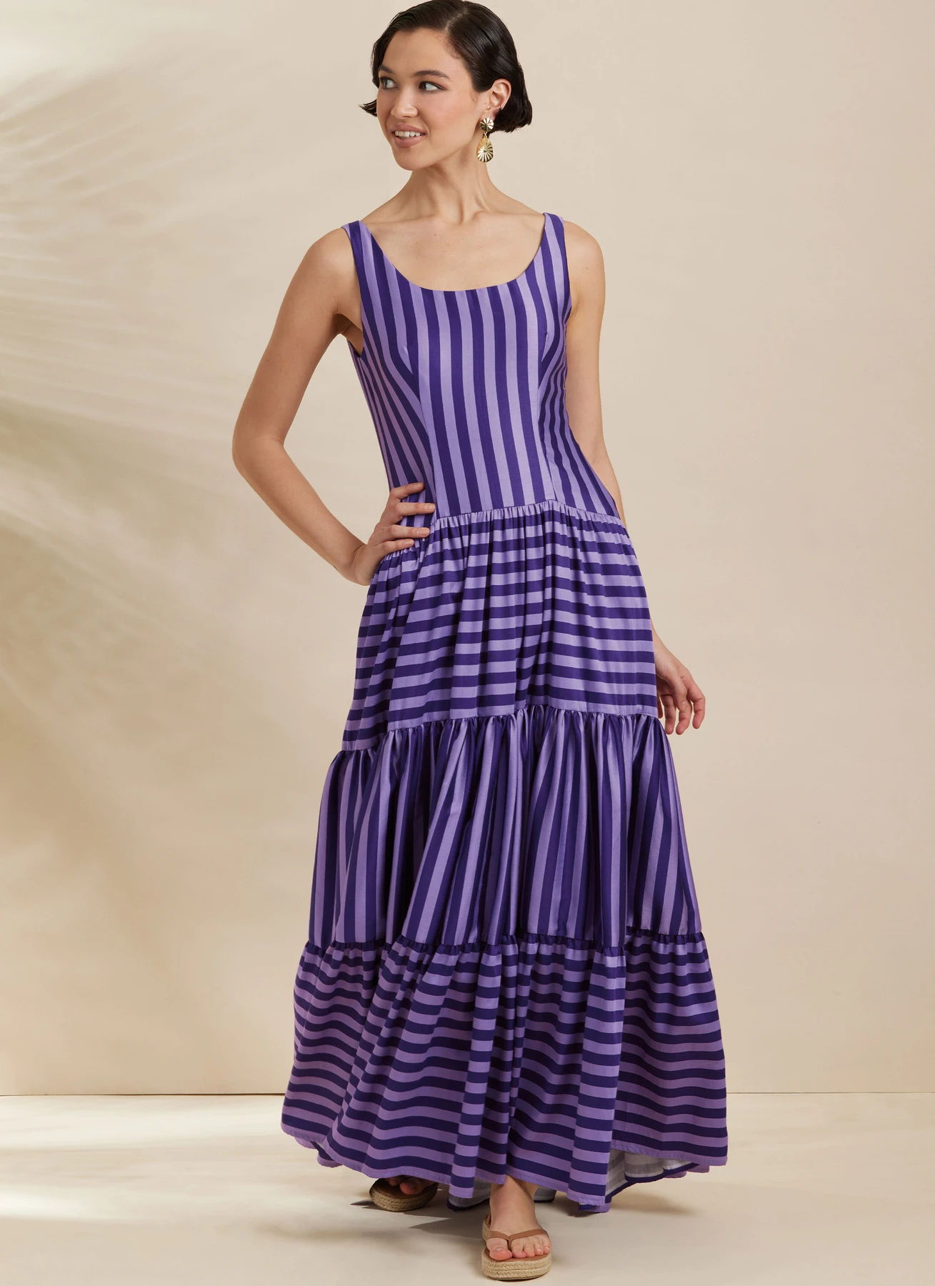 Woman in a purple striped maxi dress, posing against a neutral background.