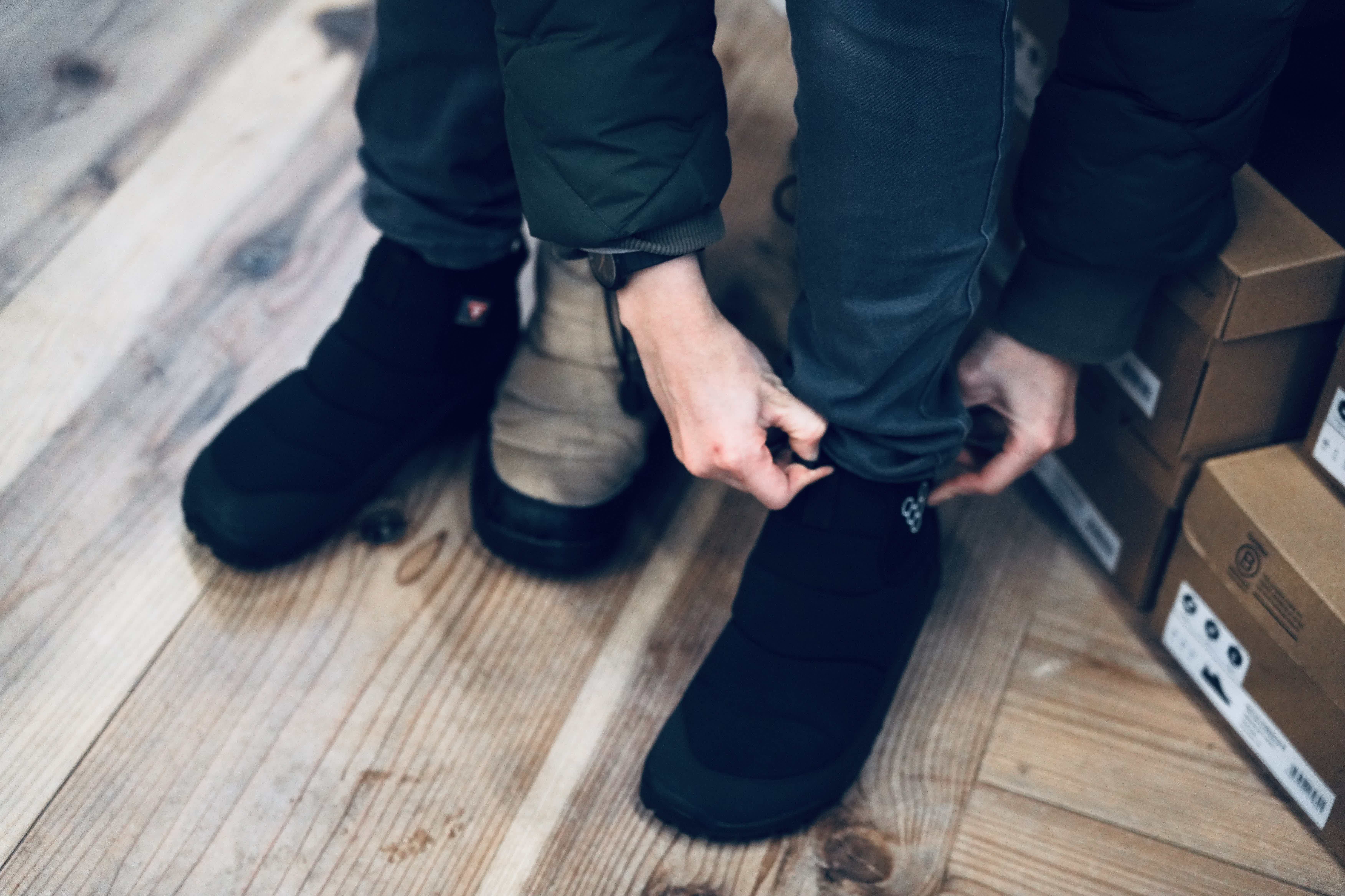 Person tying shoelaces while wearing two different shoes.