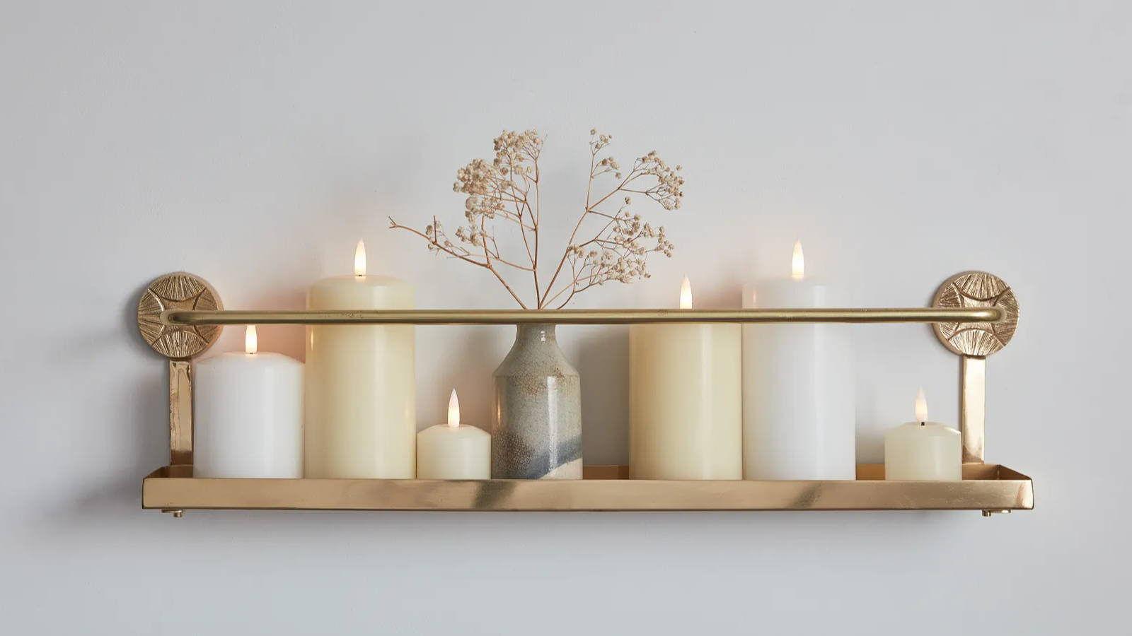 A shelf with white and ivory LED pillar and votive candles. 
