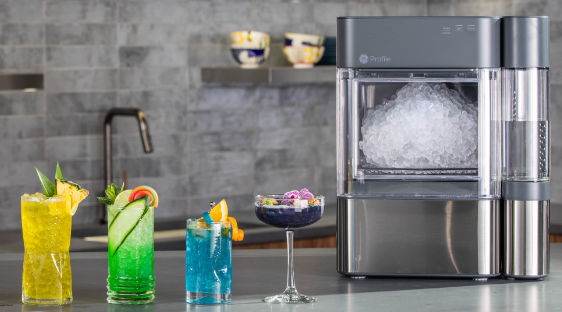 Colorful drinks beside a modern ice maker on a kitchen countertop.