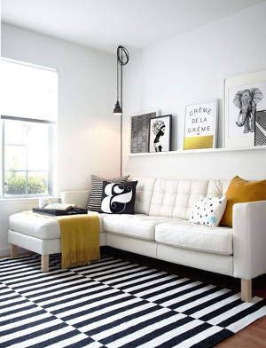 Contemporary living room with black and white decor and mustard yellow accents.