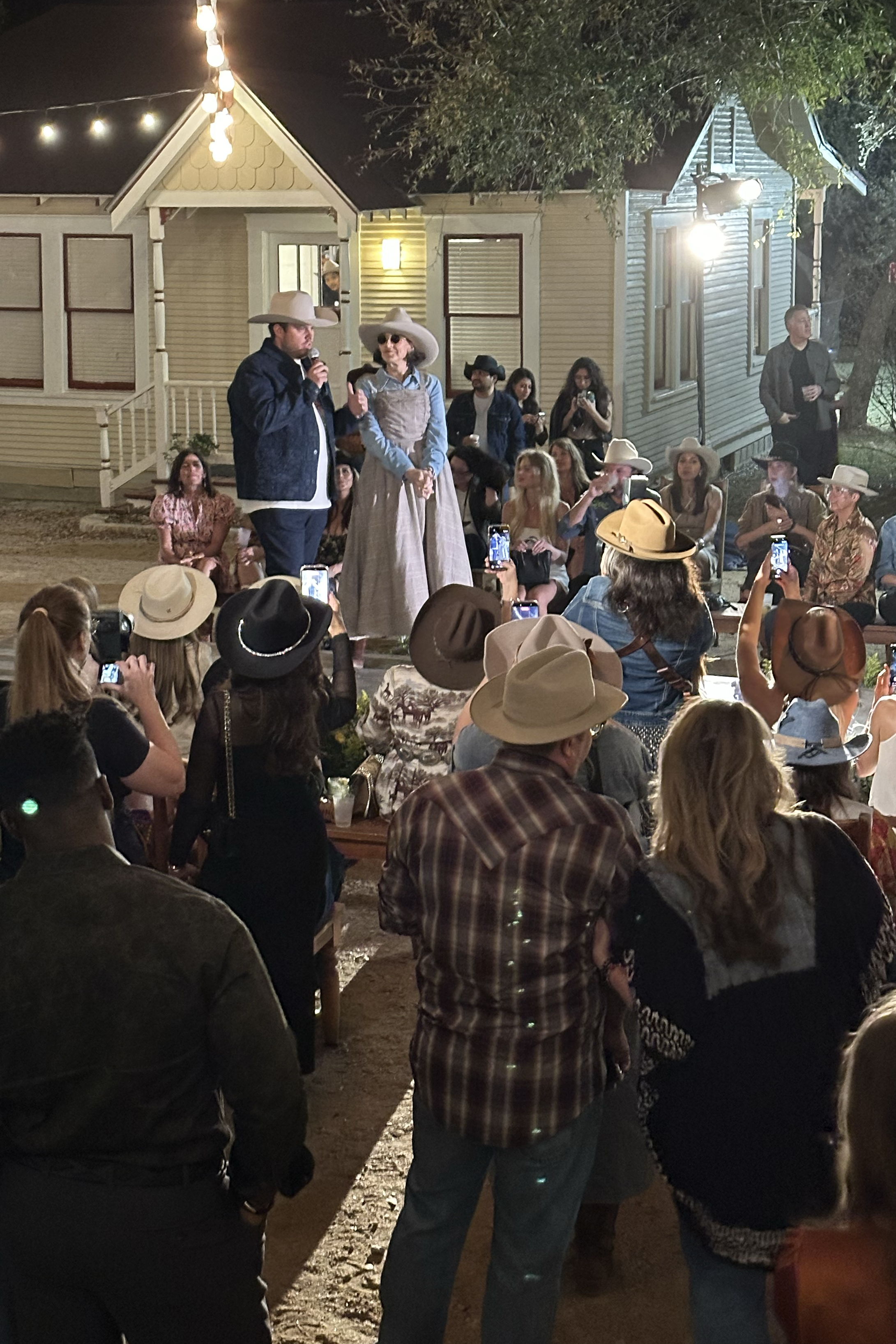 Mitchell and Cheryl on stage after the fashion show informing guests about the collections they just viewed and inviting them into the booth.