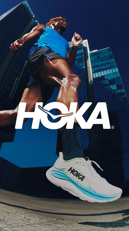Person running in HOKA shoes with city buildings in background.