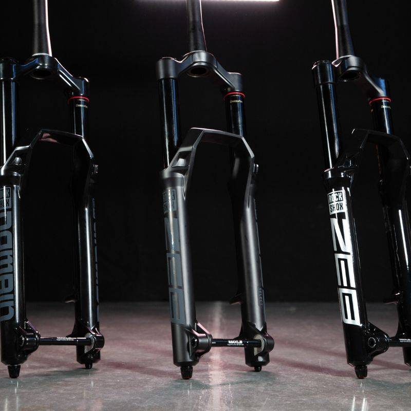 rockshox domain and zeb forks on concrete floor with black background