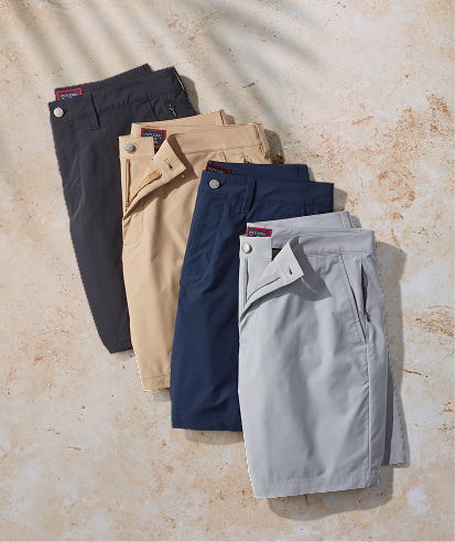Four pairs of shorts in different colors on a sandy background.