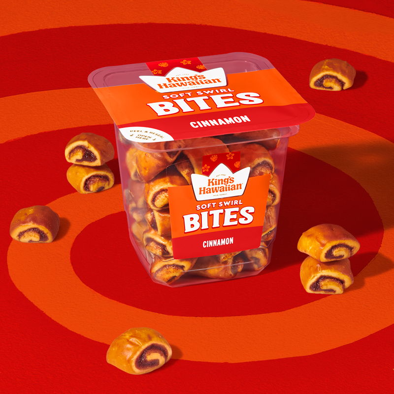 Container of cinnamon bites on a red background with scattered pieces around it.