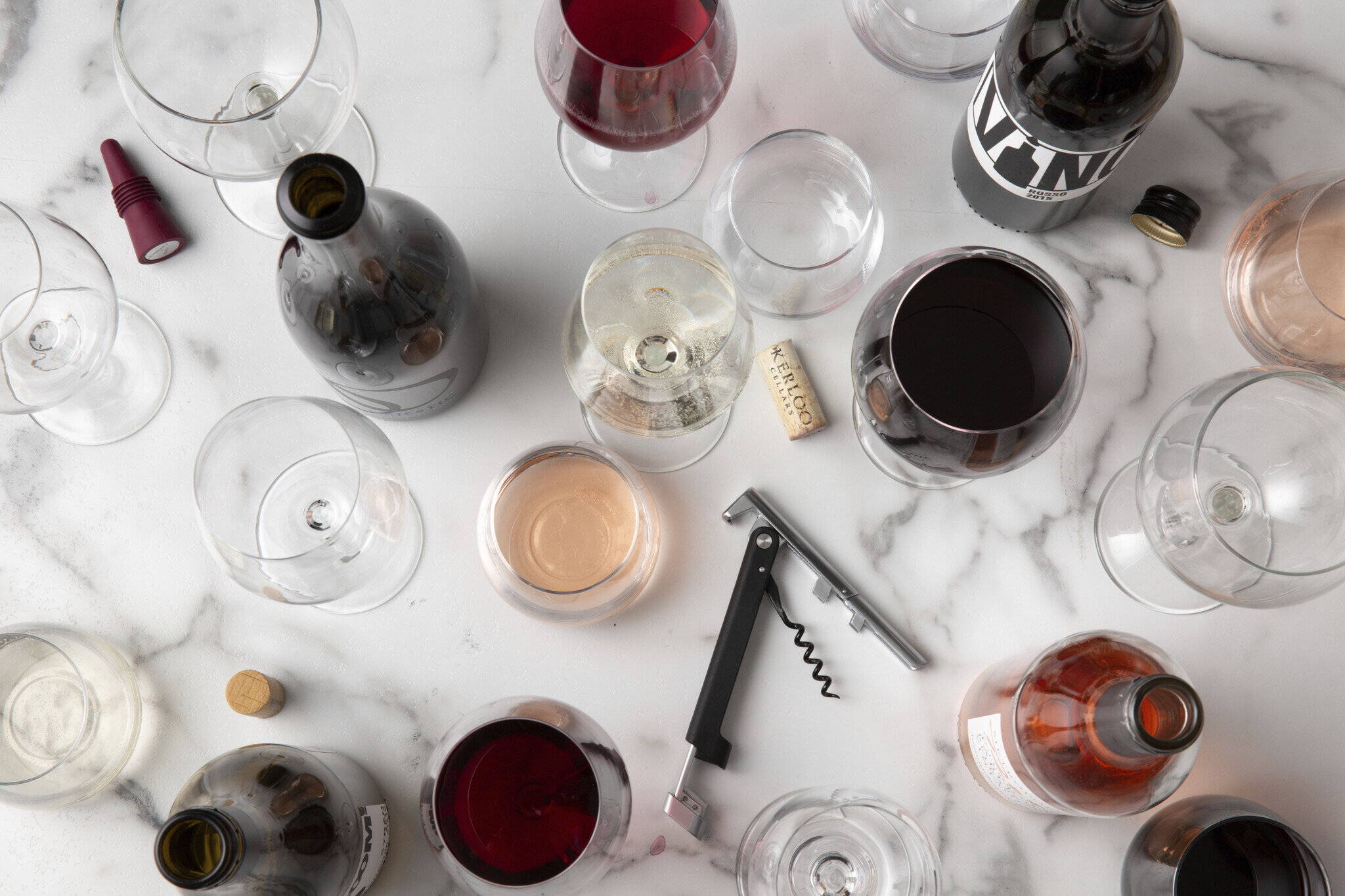 Wine glasses, bottles, and a corkscrew on the kitchen table.