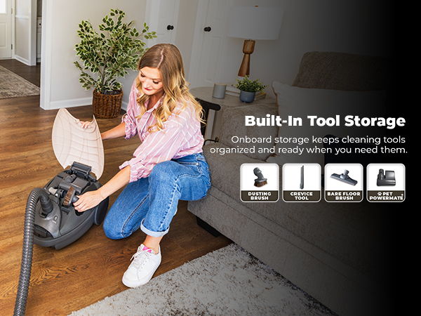 Person using a vacuum cleaner with built-in tool storage in a living room.