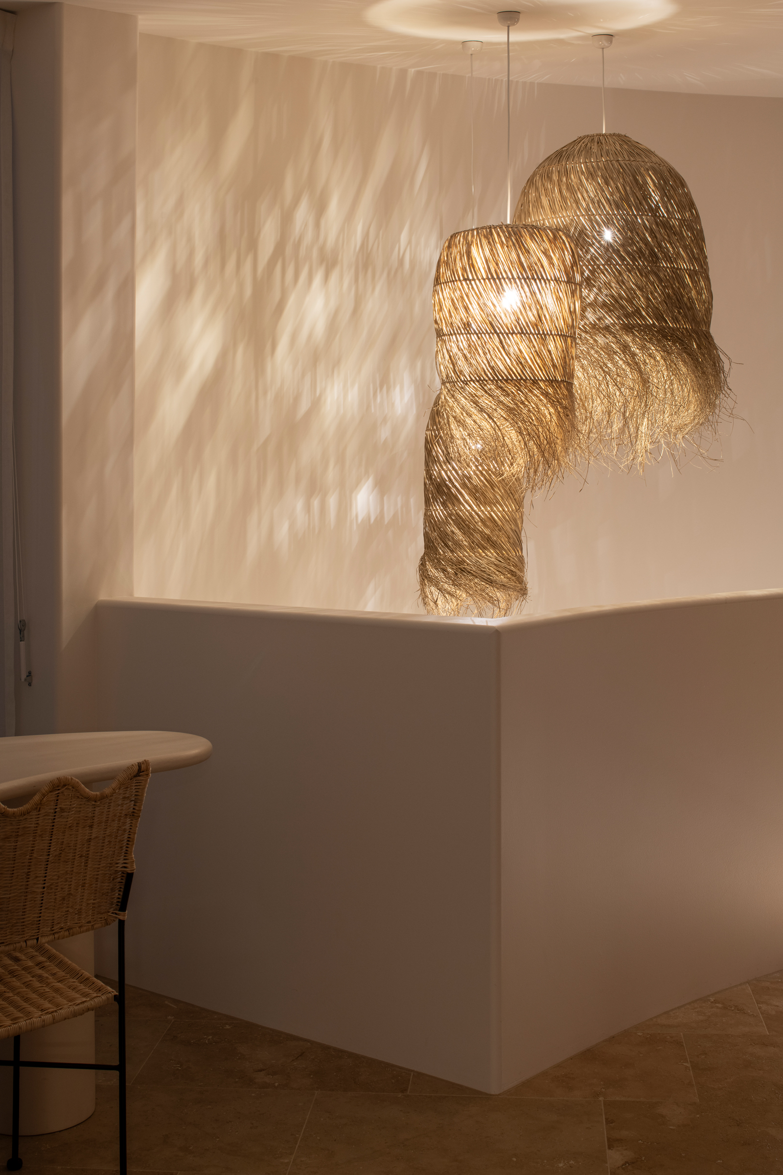 Stylish interior with woven pendant lights casting shadows on a white wall.