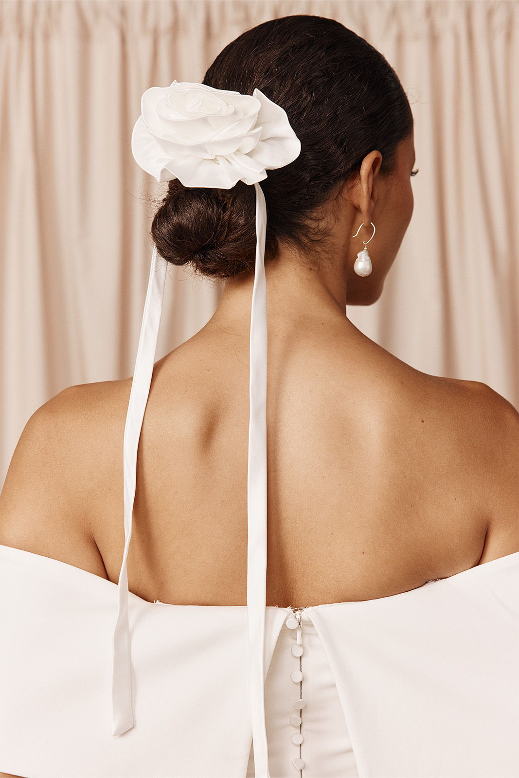 A woman with a floral hair accessory and ribbons, seen from the back.