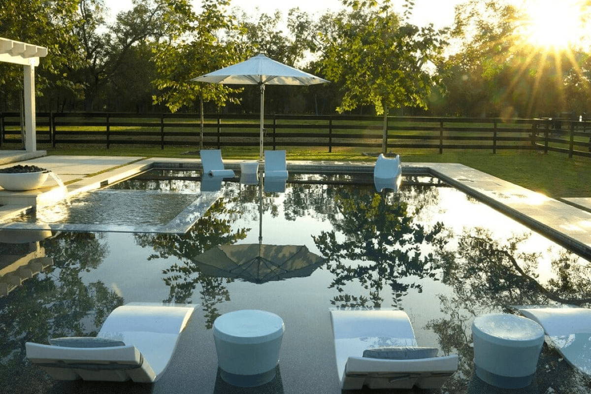 In-pool chaise lounge chairs and umbrellas under the sun, creating a serene and inviting poolside atmosphere.