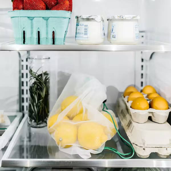 reusable product bags and glass food containers in refrigerator