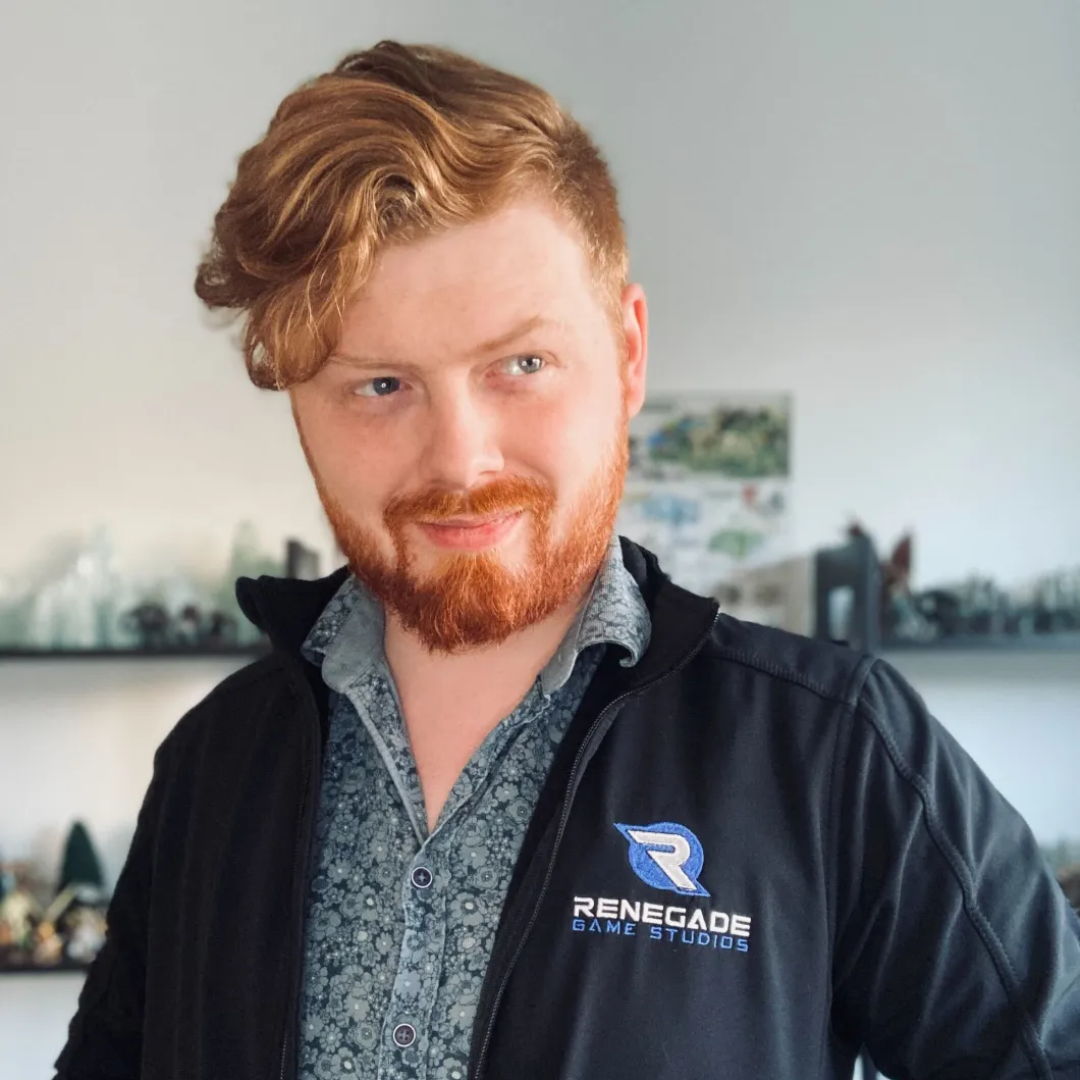 Person with curly red hair wearing a black jacket and blue shirt, smiling.