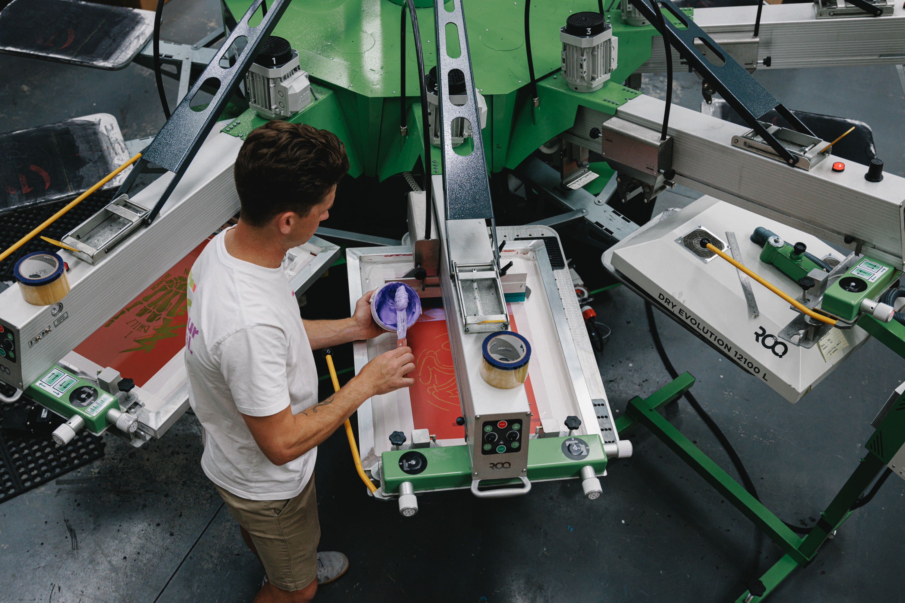 Person operating a screen printing machine in a workshop.