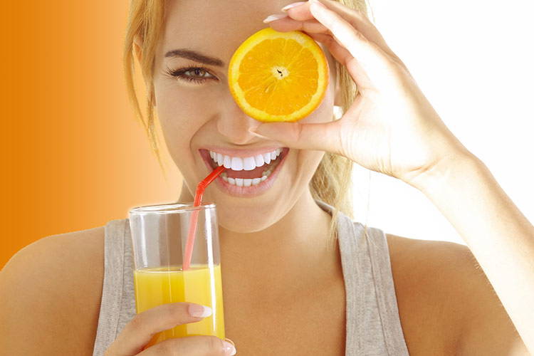 Woman Drinking Orange Juice And Holding An Orange Over Her Eye