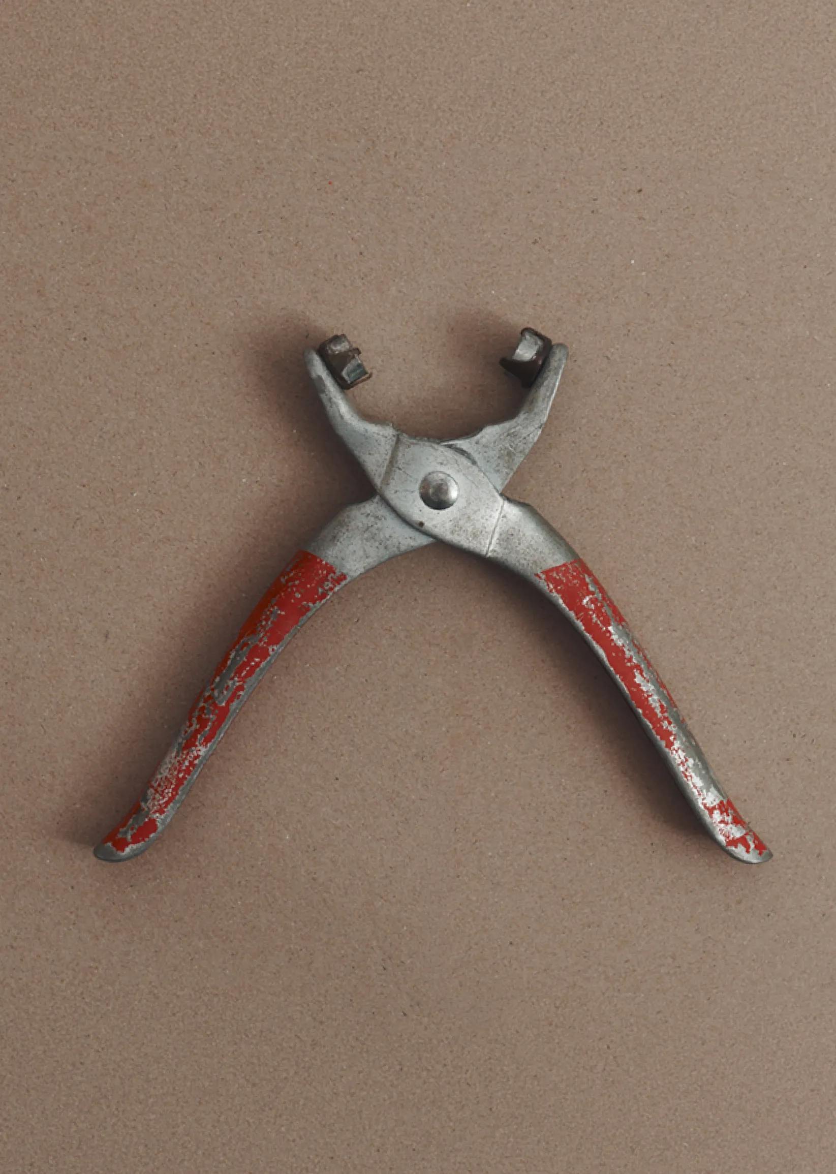 A metal tool with red handles, used for gripping or pulling.