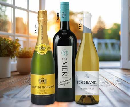 Three bottles of wine displayed on a table near a window.