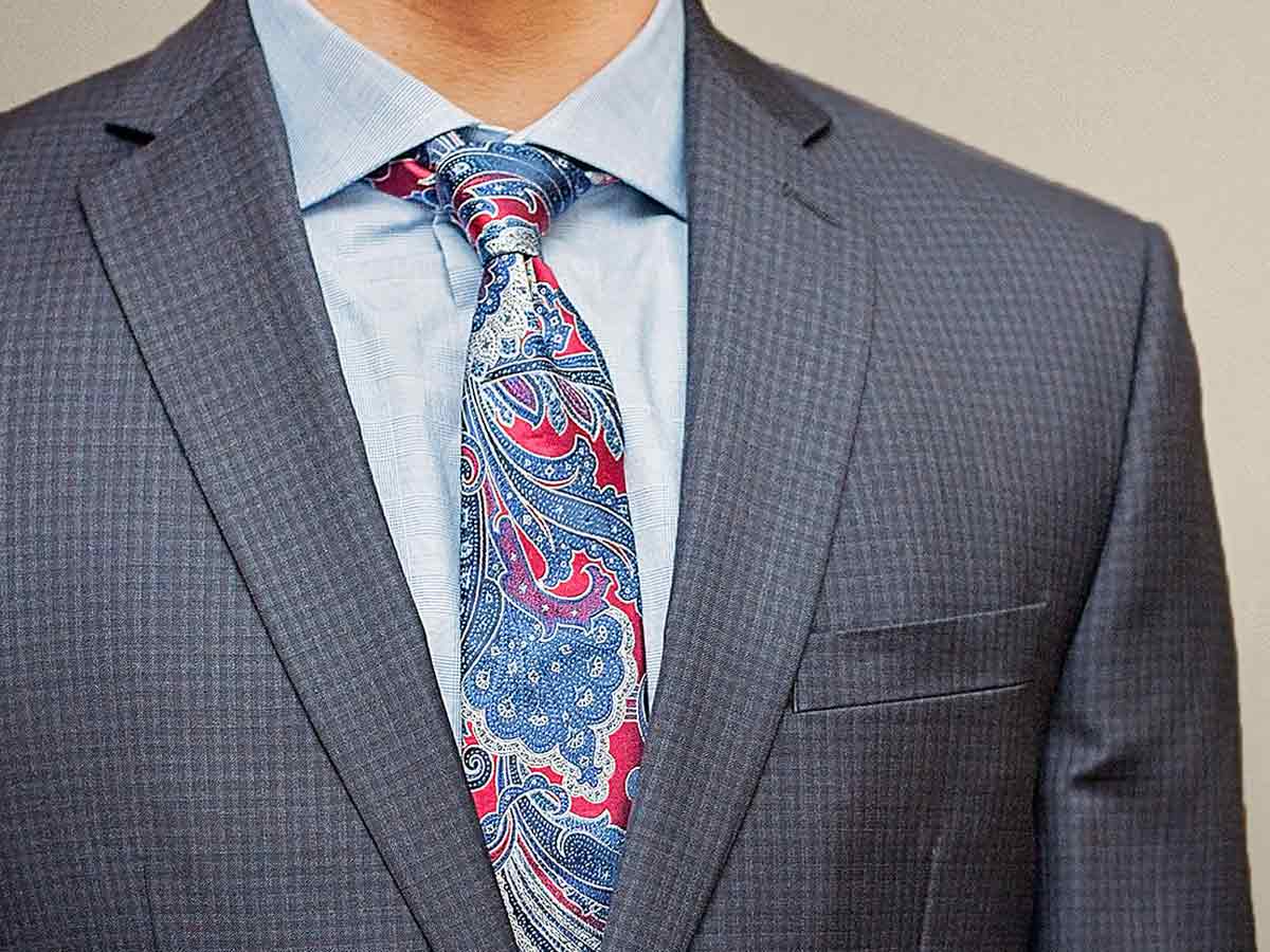 Business man wearing a blue and crimson red paisley tie with a blue shirt and checked suit.