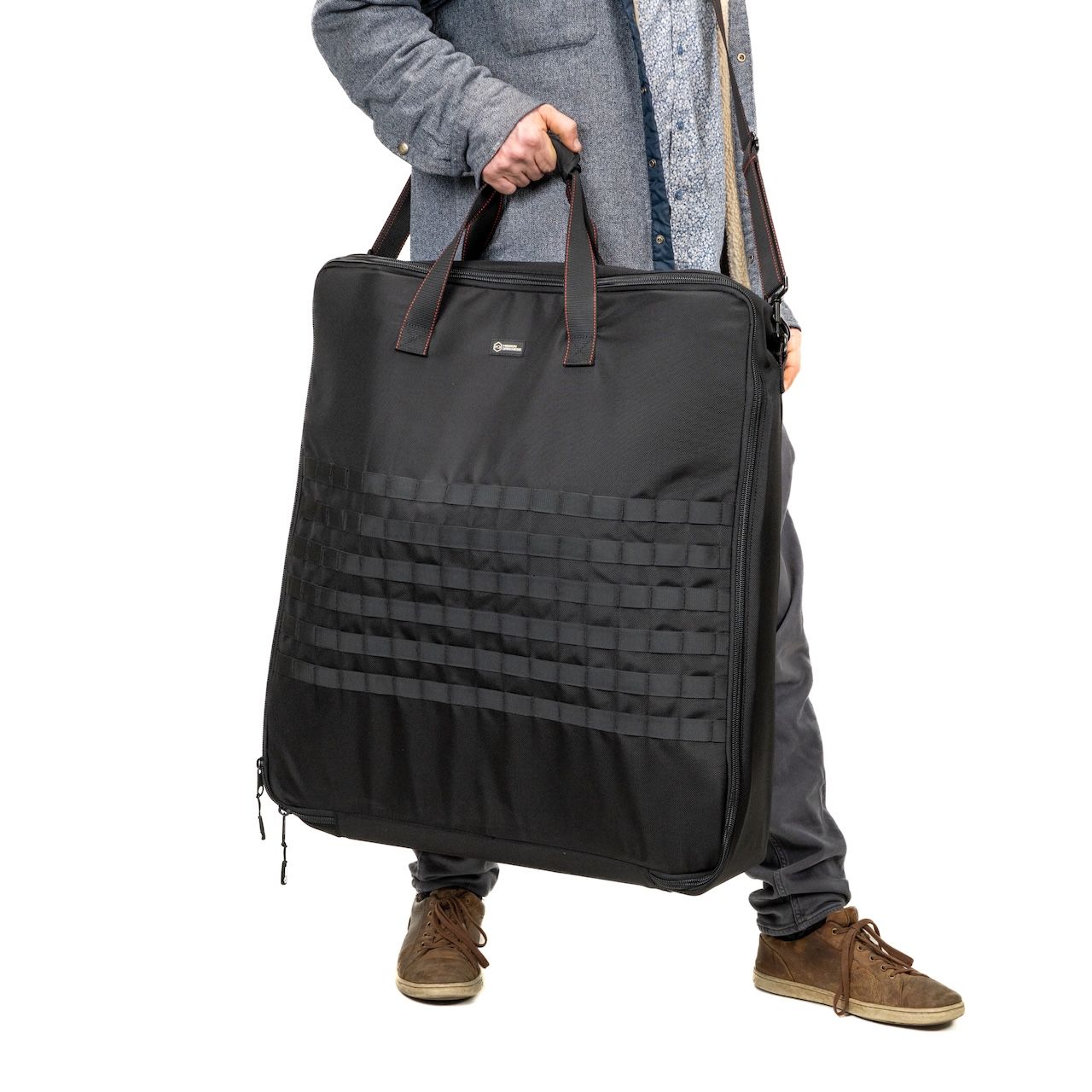 Person holding a large black bag with handles.
