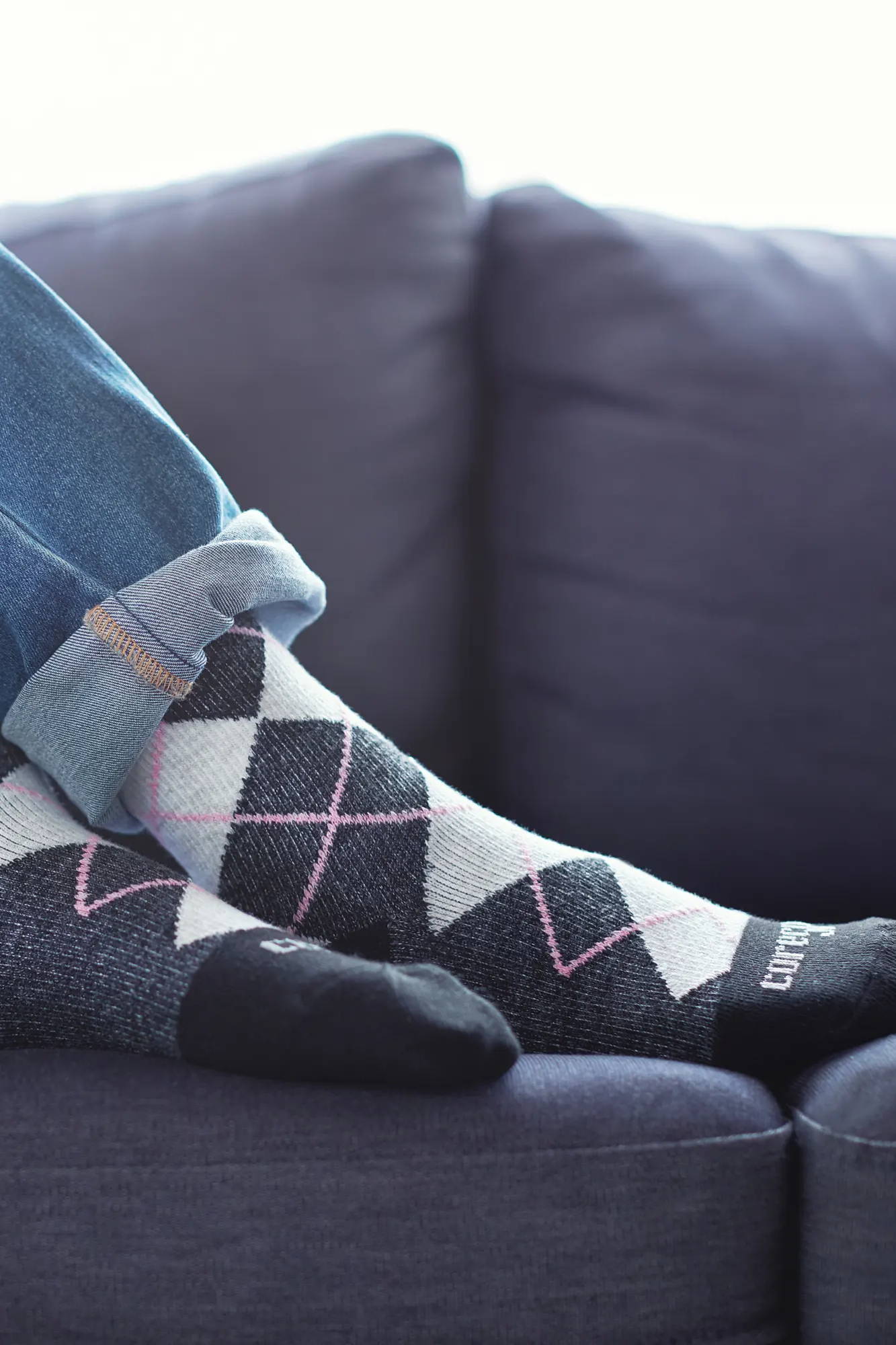 Woman lounging on couch wearing Core-Spun Gradient Compression Socks in Pink Argyle