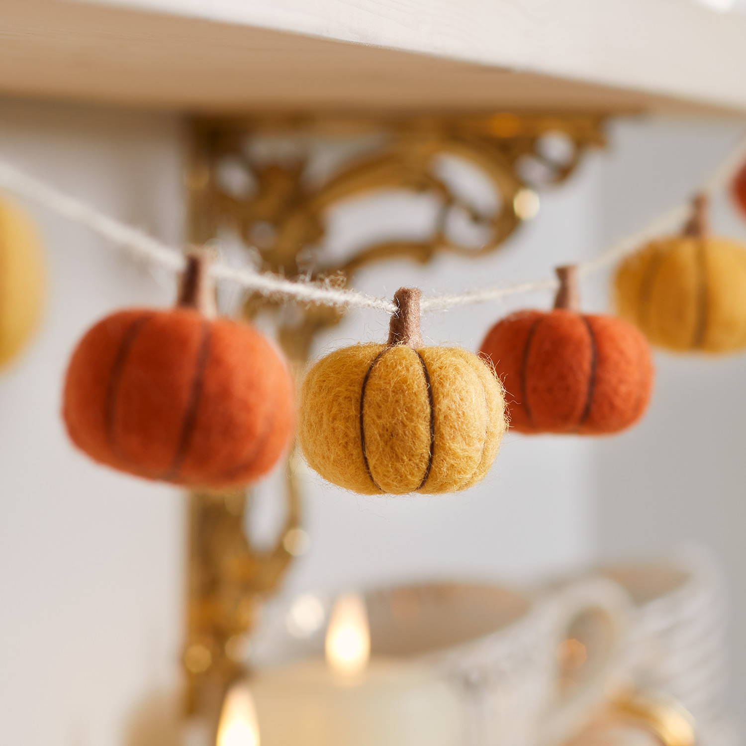 A yellow and orange felt pumpkin garland draped across a kitchen shelf.