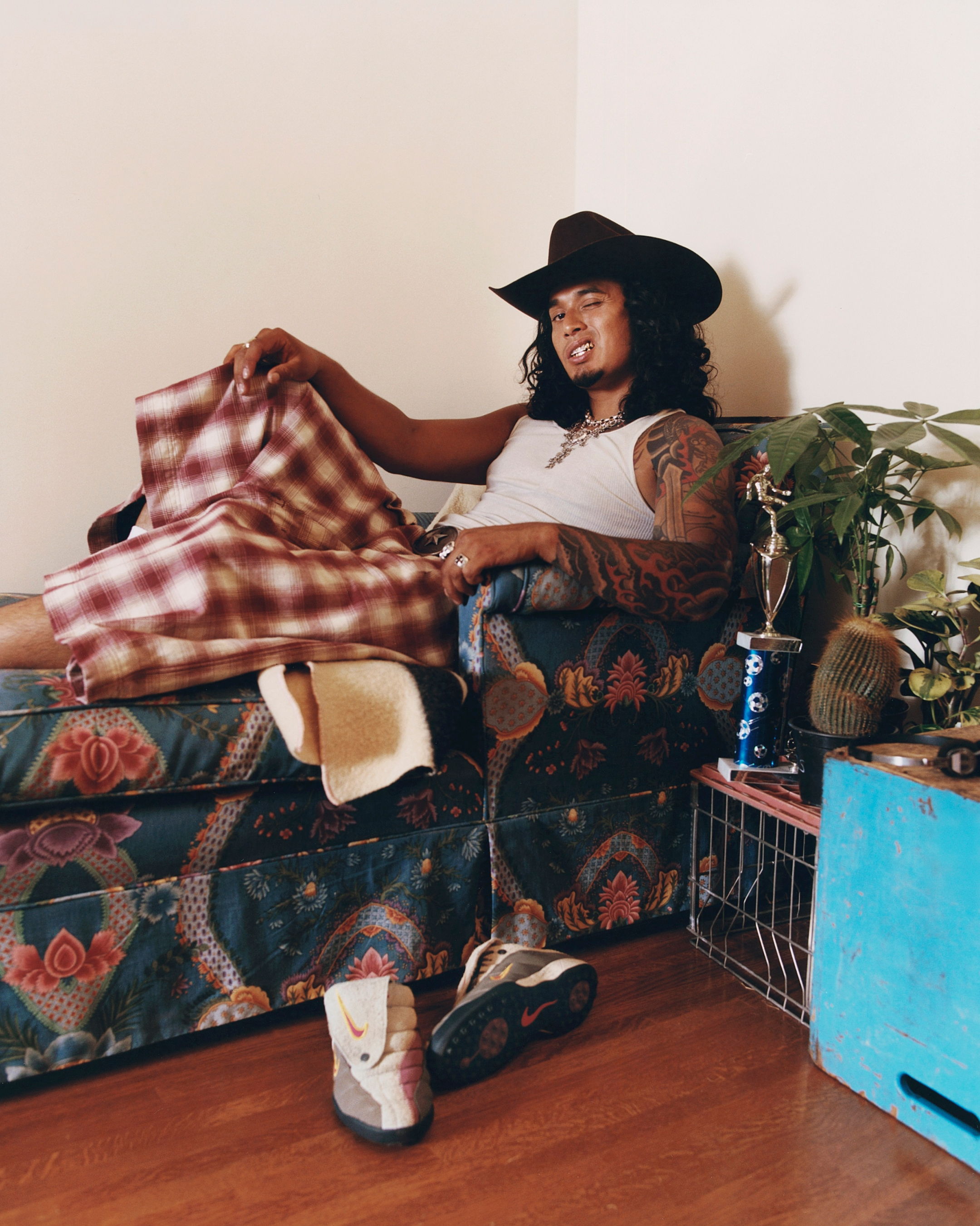 Person sitting on a couch, wearing a hat and holding fabric.