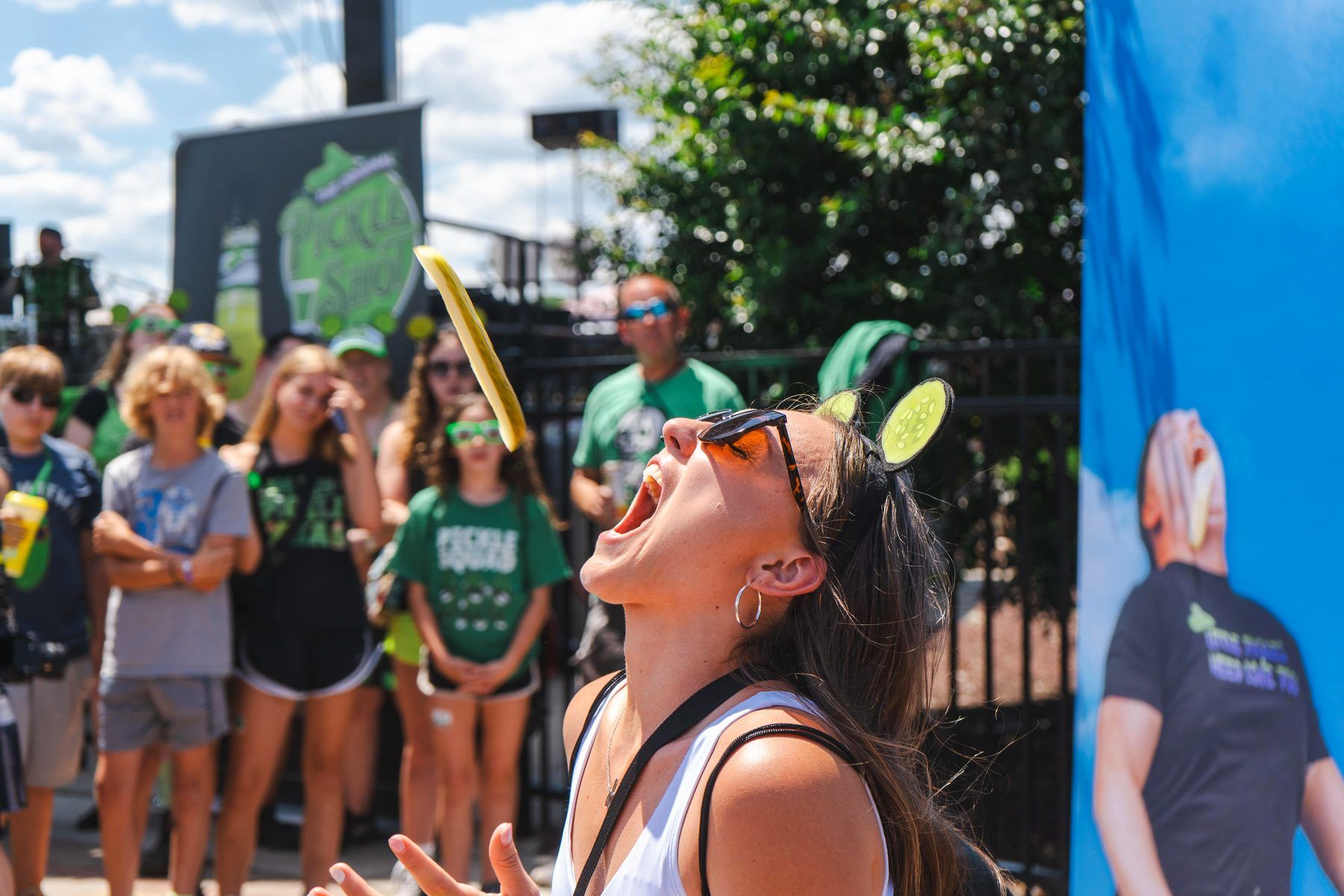 Contestant in pickle slice headband catching a tossed pickle during the Pickle Pitching activation at The Big Dill Philadelphia 2024.