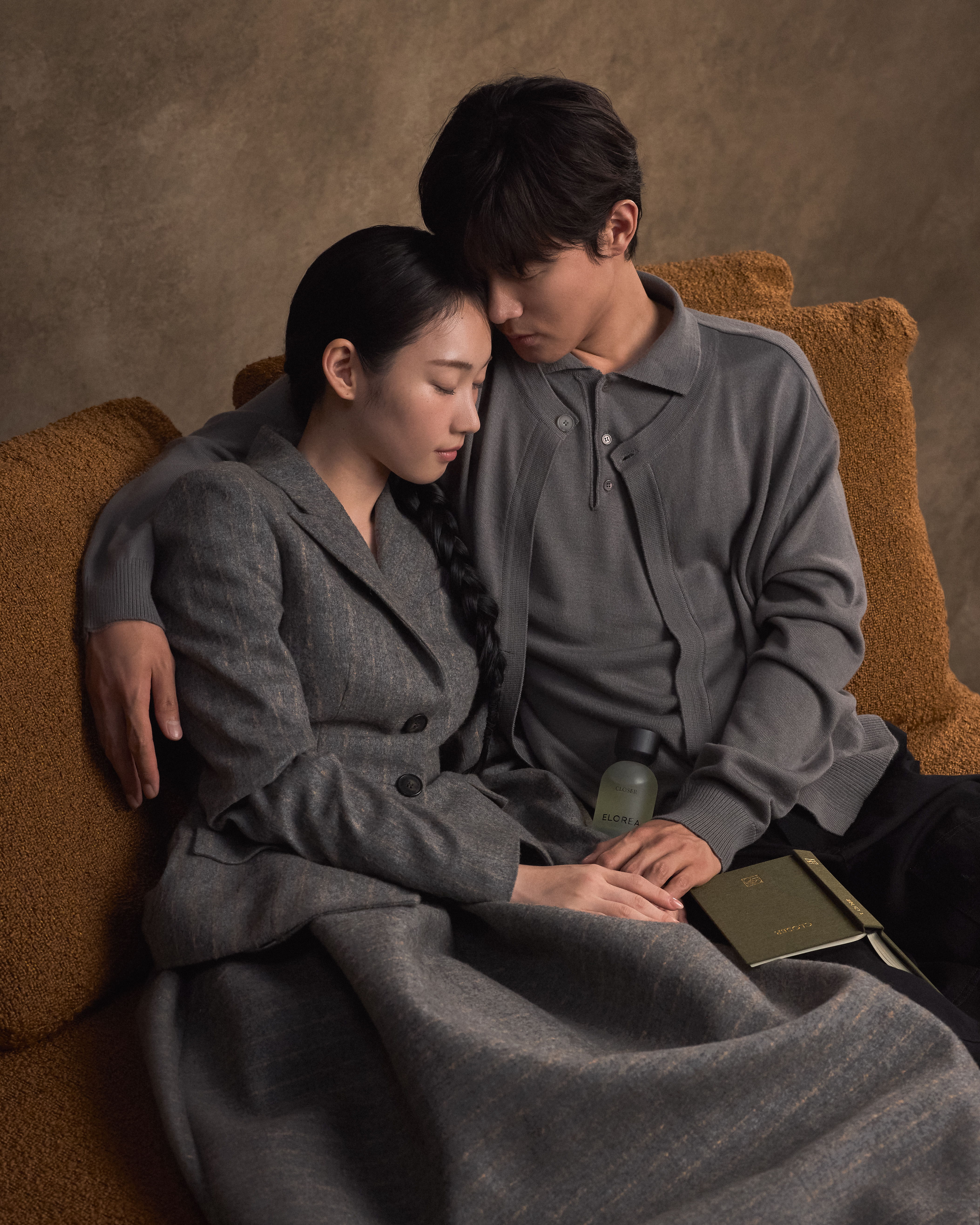 A couple sitting closely together on a couch, sharing a quiet moment.