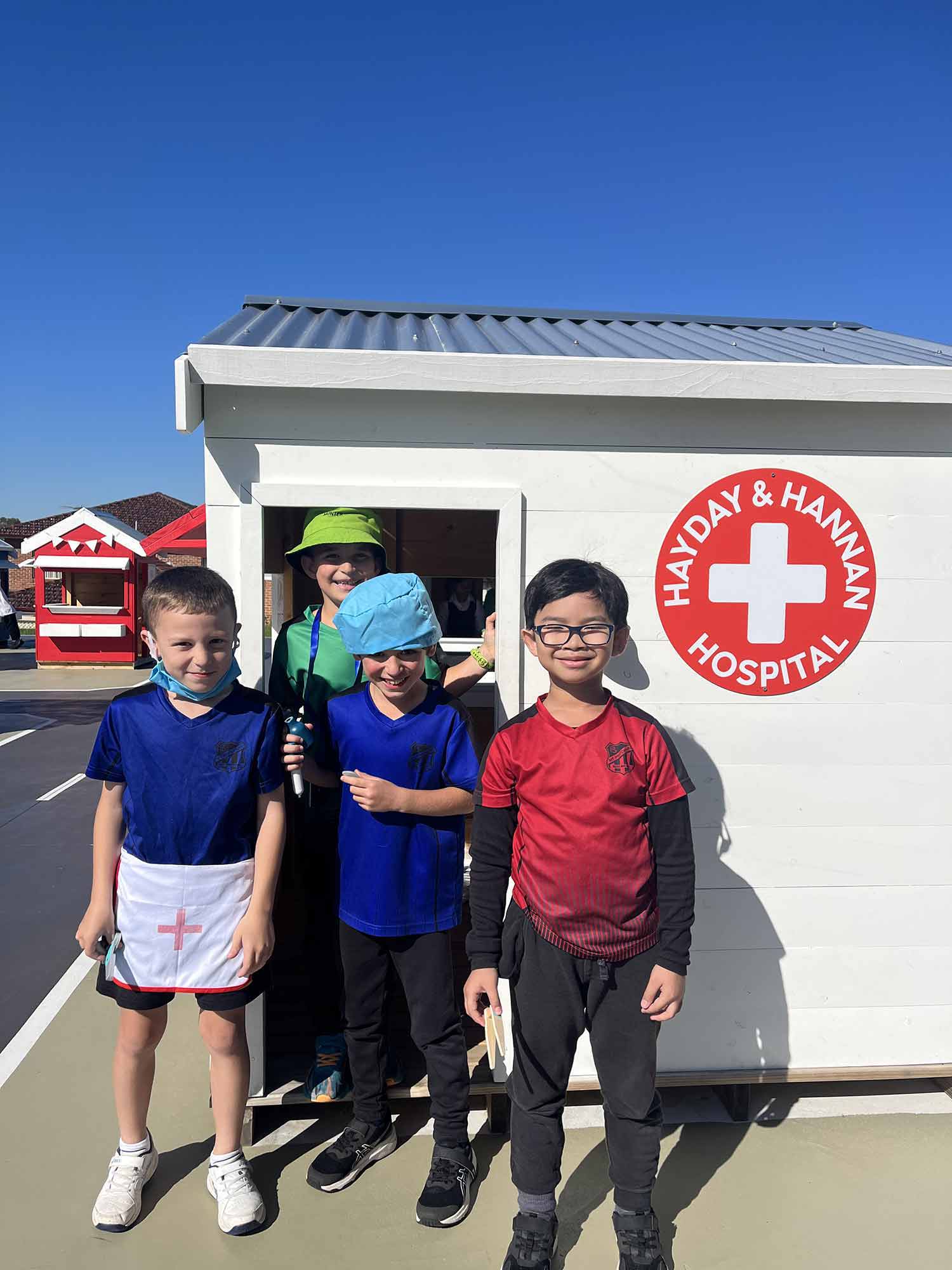 Kids pretending to be hospital workers and patients in their wooden hospital themed cubby house