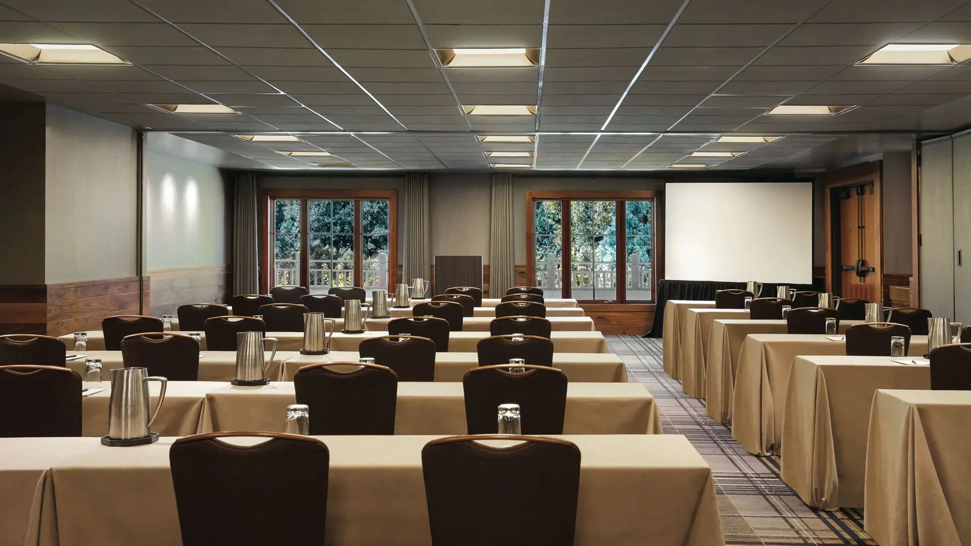 Conference room with tables, chairs, and a projector screen.