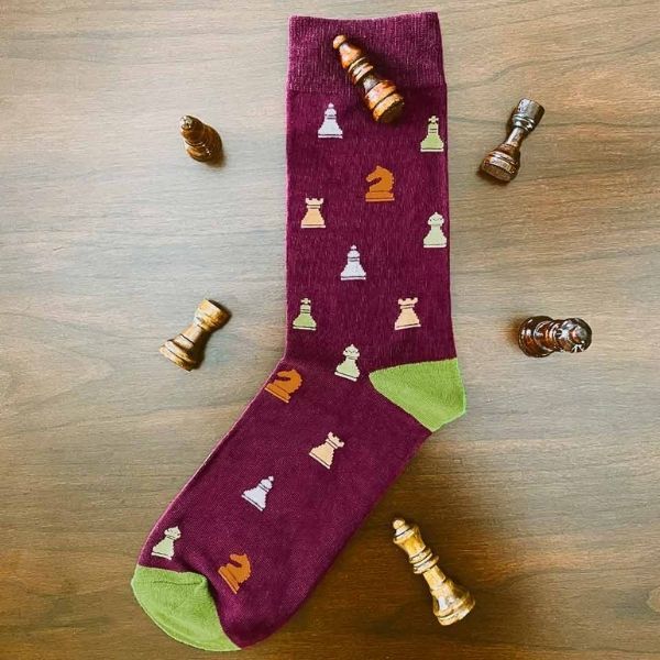 Burgundy chess themed sock spread out on wood with chess pieces