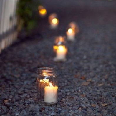 Mason jars with candles inside lighting up a walk way.