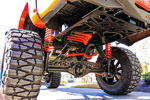 Low-angle rear undercarriage red coil springs four red train horns orange body Nitto Mud Grappler driveway Billy's Tacoma 244K gallery photo 2
