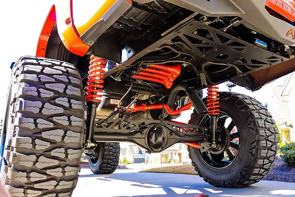 Low-angle rear undercarriage red coil springs four red train horns orange body Nitto Mud Grappler driveway Billy's Tacoma 244K gallery photo 2
